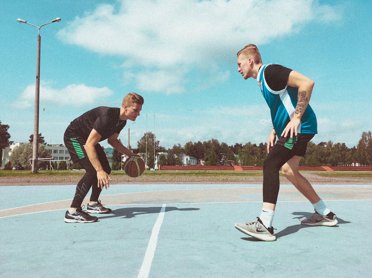 Two men playing basketball outdoors in Belarus on a sunny day, showcasing active lifestyle and sport.